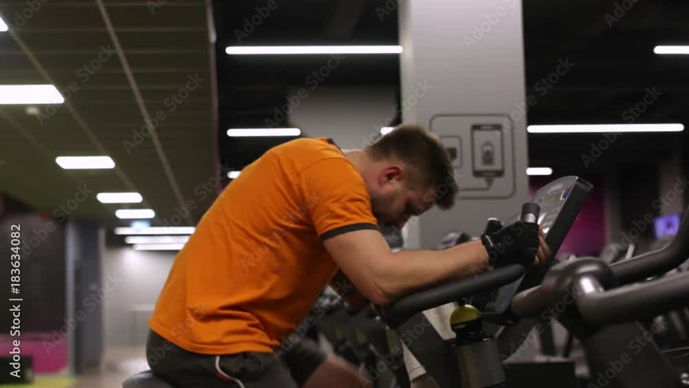 Fit man working out on exercise bike at the gym Fit man working out on exercise bike at the gym