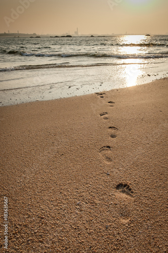 beach, wave and footprints at sunrise time