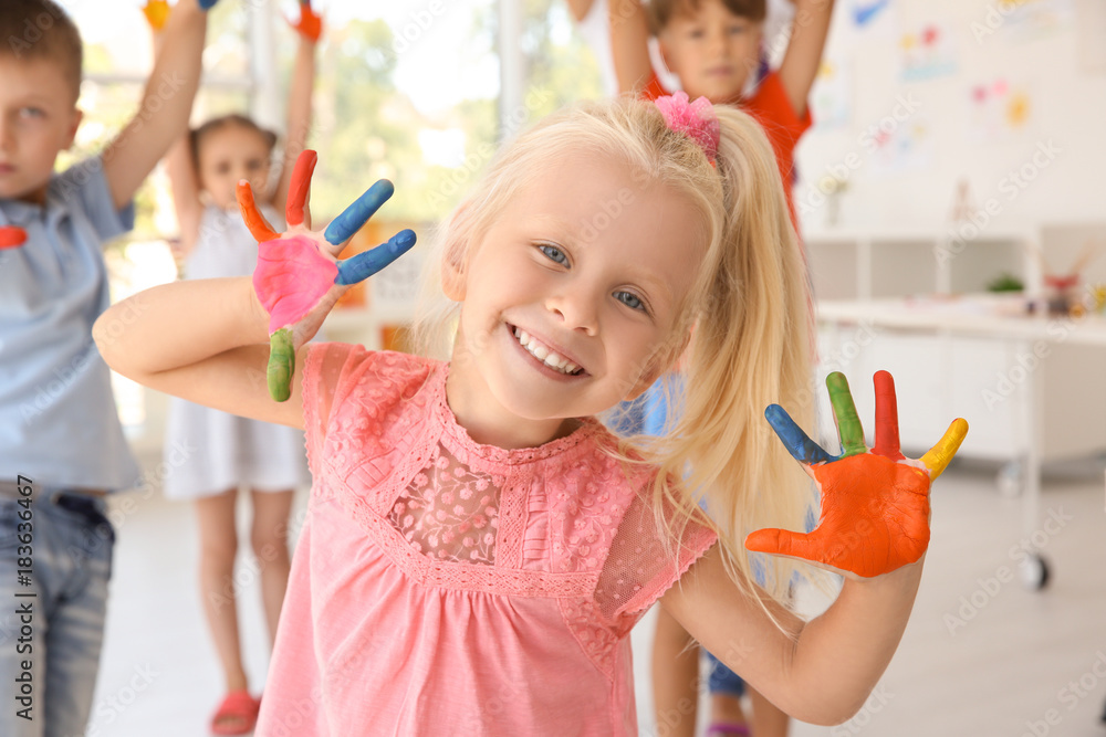 Fototapeta premium Little girl with hands in paint at art lesson