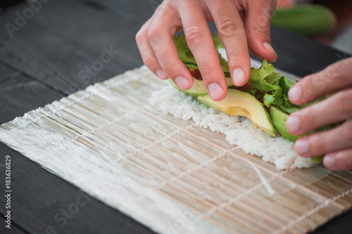 closeup of chef hands rolling up sushi photo