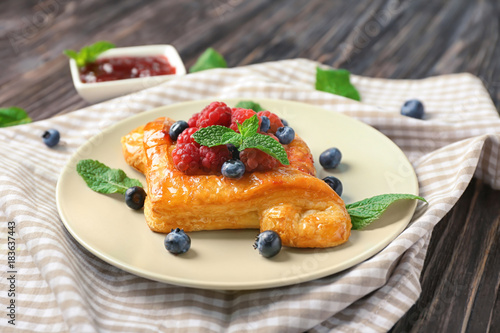Plate with yummy berry puff pastry on table
