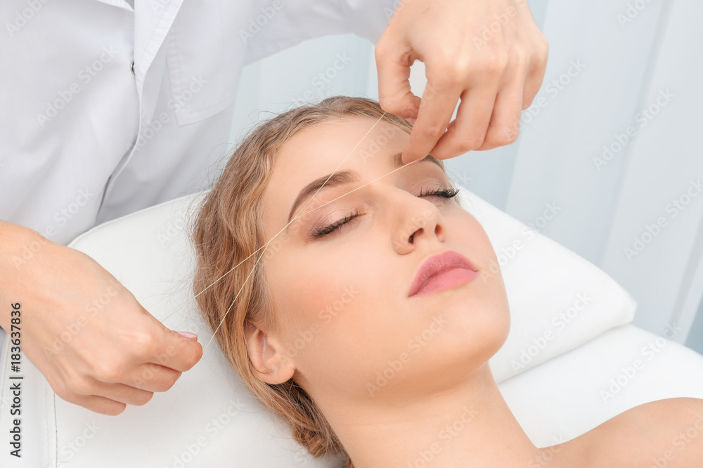 Young woman having eyebrow correction procedure in beauty salon Young woman having eyebrow correction procedure in beauty salon