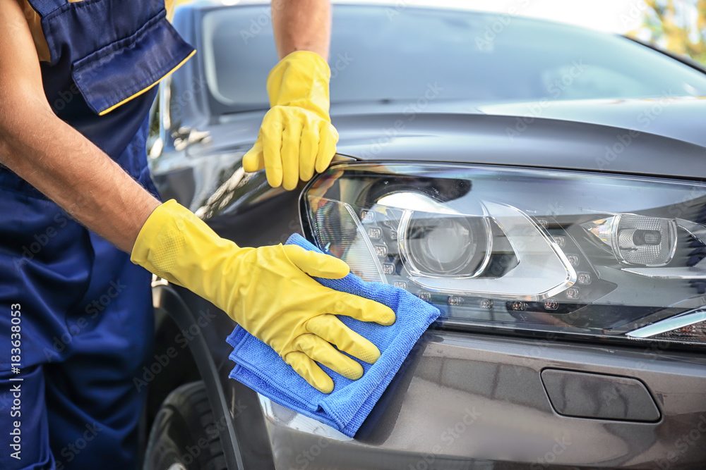 Man cleaning car headlight with rag outdoors Man cleaning car headlight with rag outdoors