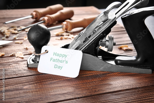 Card with text Happy Father's Day and bench plane on wooden table
