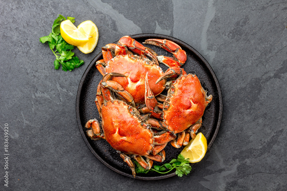 Cooked whole crabs on black plate served with white wine, black slate background, top view Cooked whole crabs on black plate served with white wine, black slate background, top view