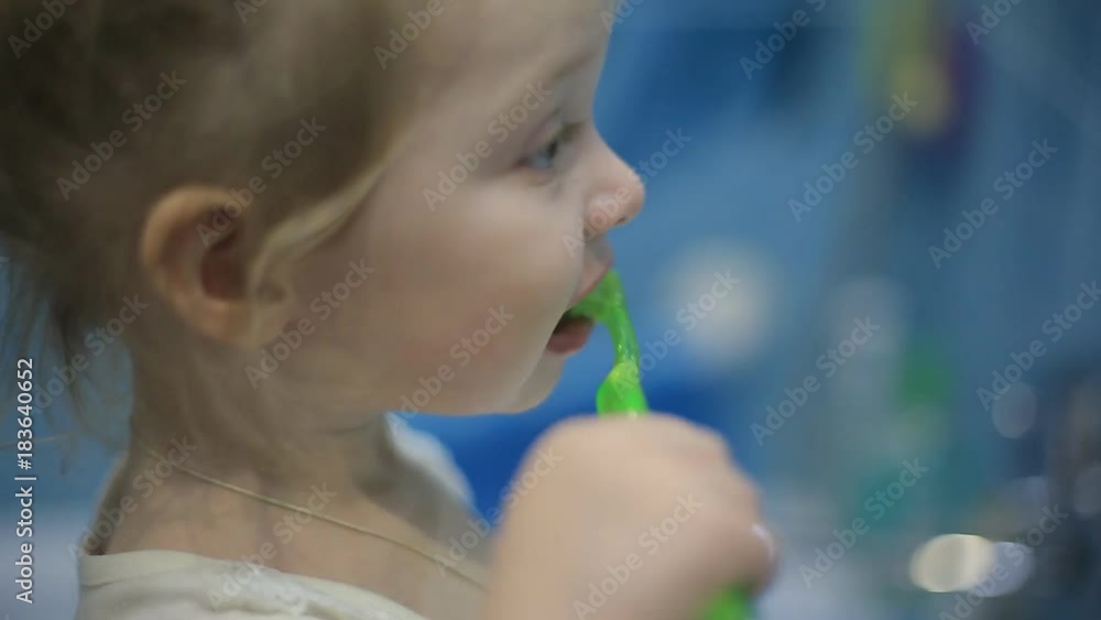 Little child girl face portrait brushing her teeth with a toothbrush in bathroom in the morning Little child girl face portrait brushing her teeth with a toothbrush in bathroom in the morning