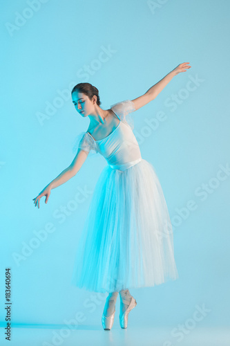 Young and incredibly beautiful ballerina is dancing in a blue studio