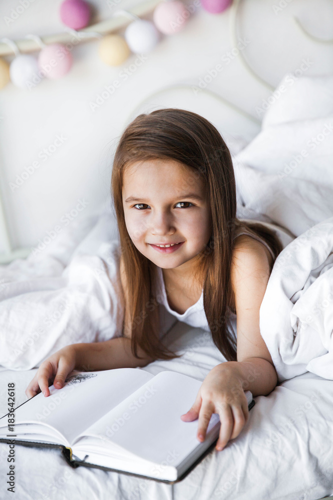Portrait of a little girl in the bed reading a book. Activities, hobbies Portrait of a little girl in the bed reading a book. Activities, hobbies