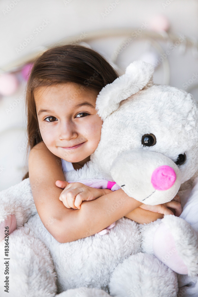 Little girl with her teddy sitting on the bed. home, comfort, family, relationships, people Little girl with her teddy sitting on the bed. home, comfort, family, relationships, people