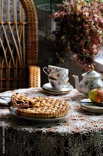 On the summer veranda on the table, an apple pie with a dough lattice
