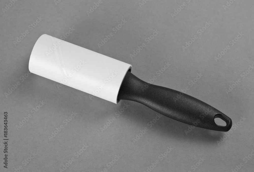 Clean Lint Roller Brush with Black Handle on Grey Background. Clean Lint Roller Brush with Black Handle on Grey Background.