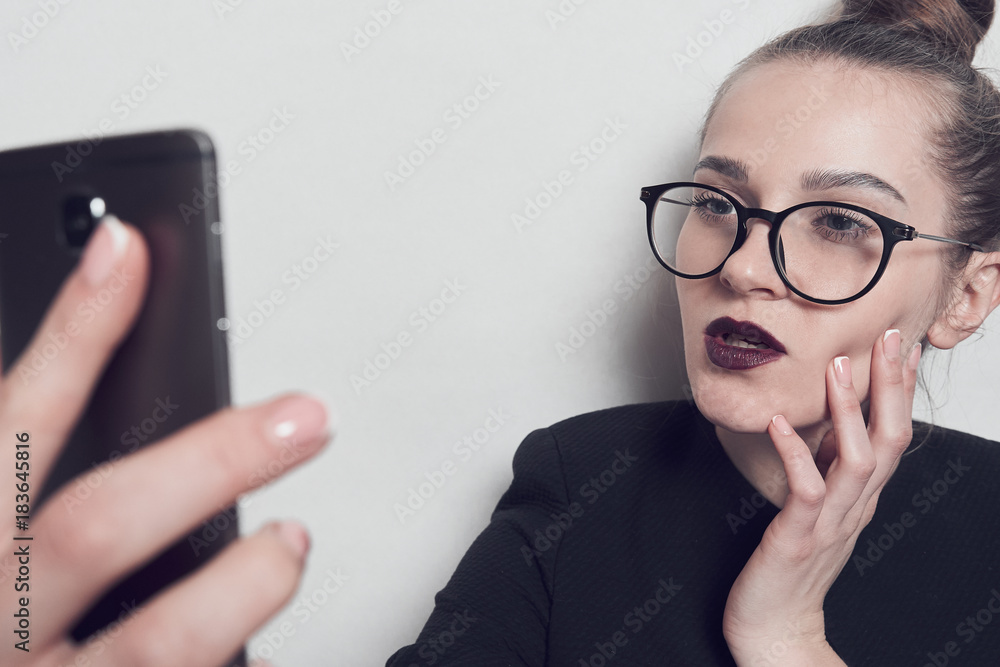 Businesswoman does selfie. The girl in black glasses. Smartphone in hand. Businesswoman does selfie. The girl in black glasses. Smartphone in hand.