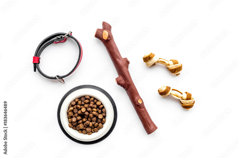 Φωτογραφία Toys for dog stick and ribbon bone near collar, dry food in bowl on white backgr