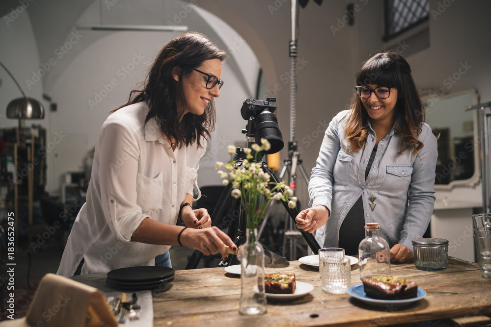 Pregnant woman with a colleague working on a food photoshoot in a studio Pregnant woman with a colleague working on a food photoshoot in a studio