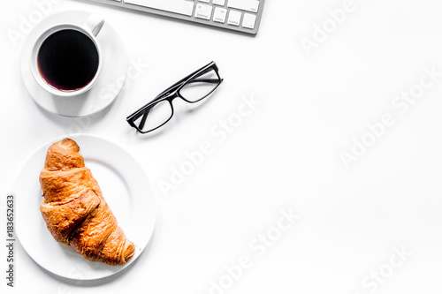 glasses, croissant and cup of coffee on office desk for business photo