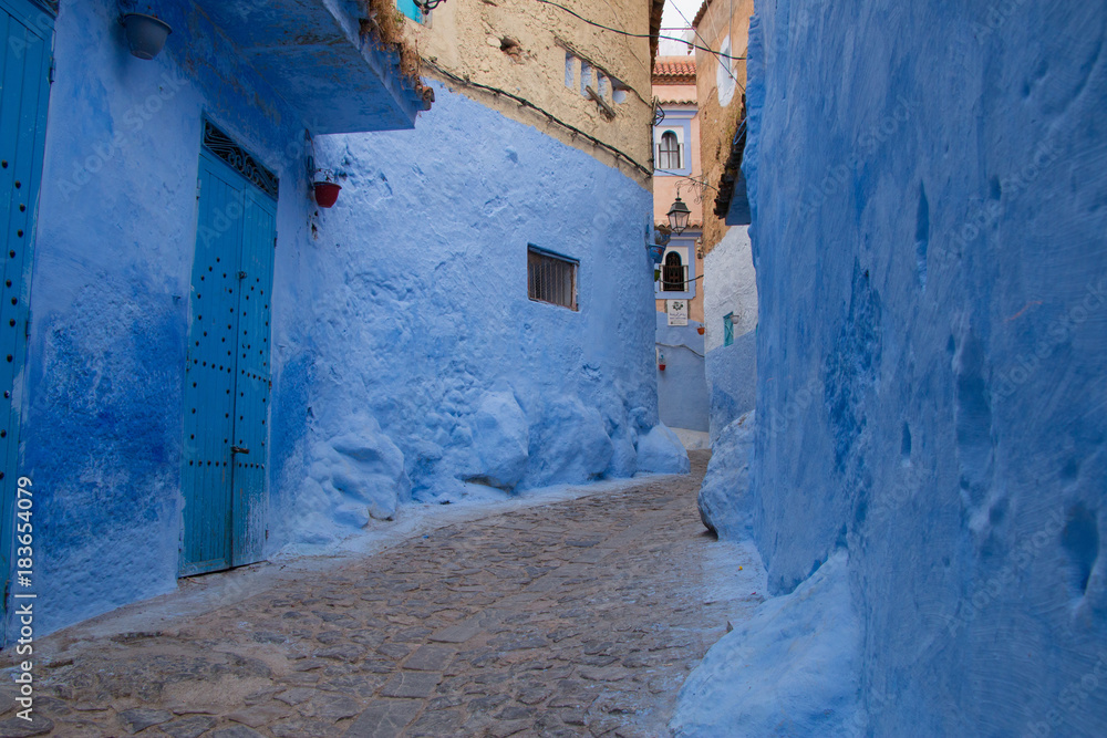 Fototapeta premium Traditional moroccan courtyard in Chefchaouen blue city medina in Morocco, architectural details in Blue town Chaouen. Typical blue walls and colorful flower pots.