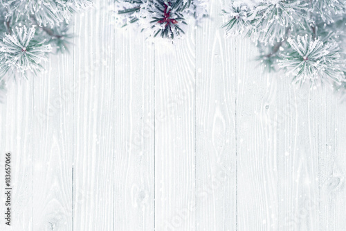 Holiday background, frosted pine tree branches over wooden texture