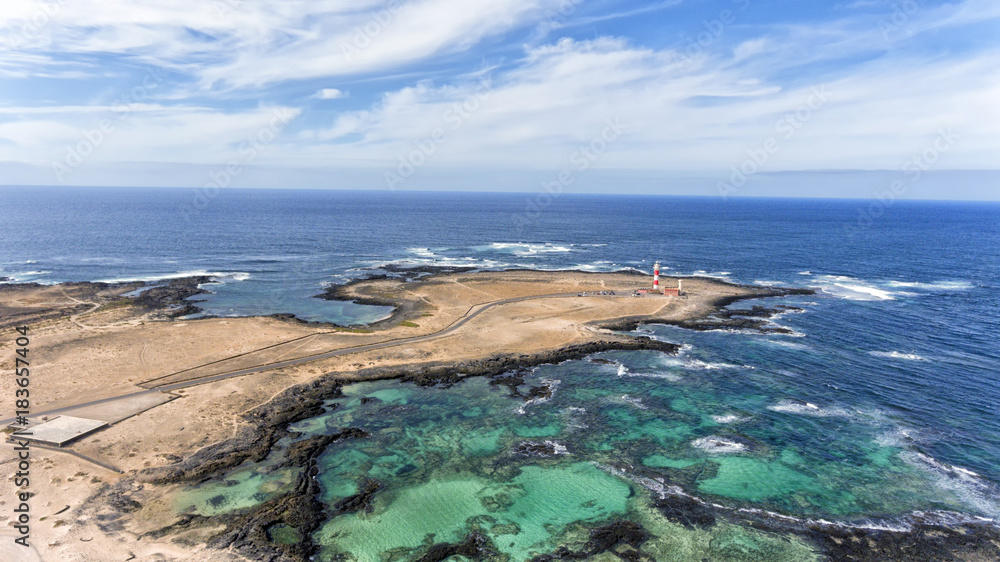Aerial view of lighthouse, turquoise lagoons, sandy beaches, rocky shore in El Cotillo, Fuerteventura, Canary Islands, Spain.