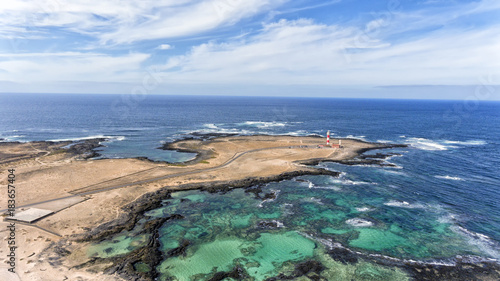 Aerial view of lighthouse, turquoise lagoons, sandy beaches, rocky shore in El Cotillo, Fuerteventura, Canary Islands, Spain.
