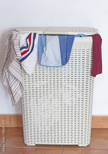 Canvas Print A dirty laundry hamper with some clothes coming out from the cover