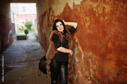 Fashion outdoor photo of gorgeous sensual woman with dark hair in elegant clothes and luxurious fur coat at old street with grunge walls. © AS Photo Family