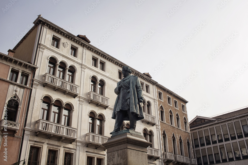 View of Daniele Manin statue from the 1875 monument by Luigi Borro in Venice.  Old, historical building are in the background with sunlight in early in the morning.