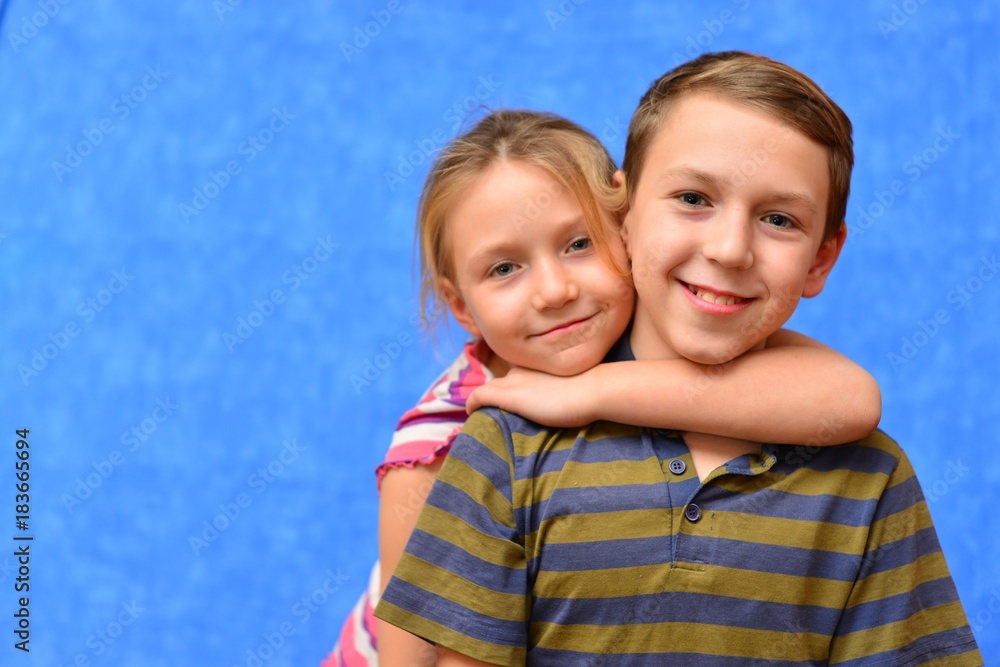 Cute couple of kids in casual clothes are giving high five, looking at camera and smiling, on gray background Cute couple of kids in casual clothes are giving high five, looking at camera and smiling, on gray background