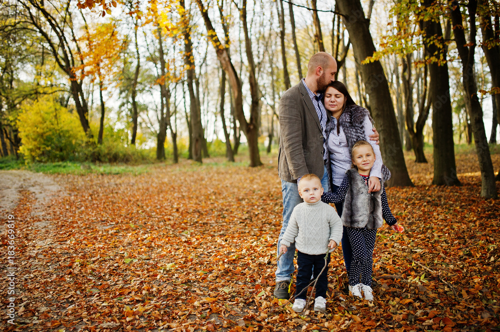 Happy caucasian family of mom dad and little girl with boy at majestic autumn fall forest.