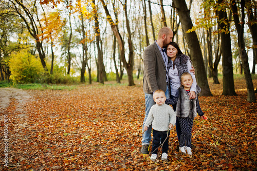 Happy caucasian family of mom dad and little girl with boy at majestic autumn fall forest.
