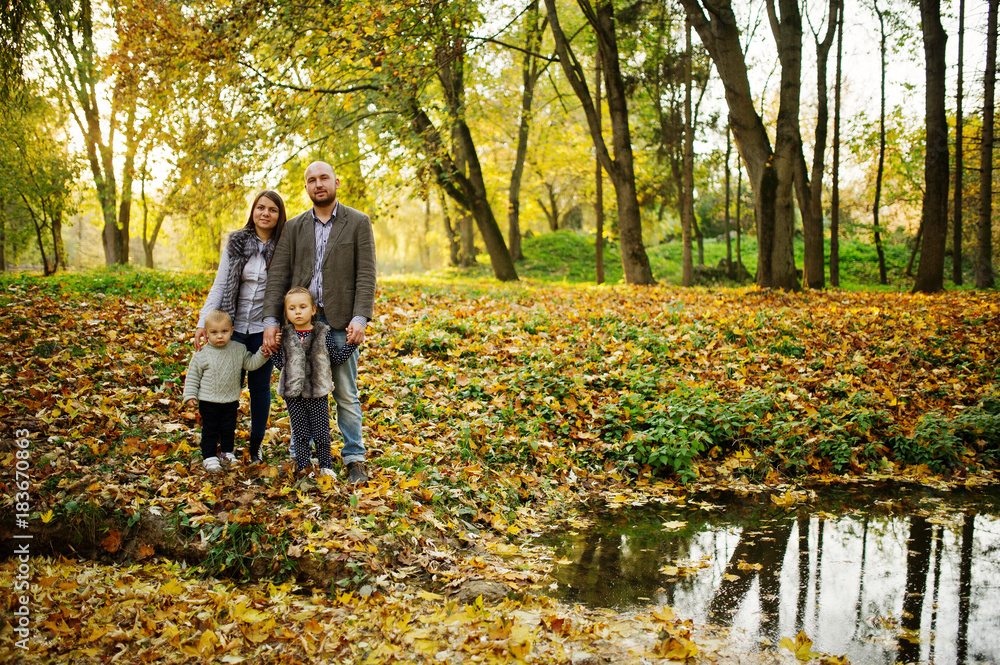 Fototapeta premium Happy caucasian family of mom dad and little girl with boy at majestic autumn fall forest.
