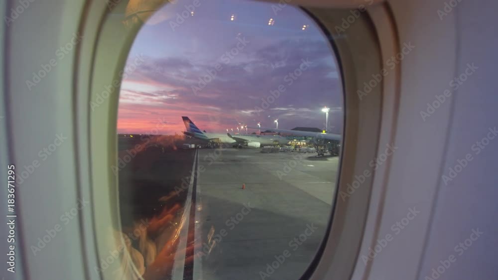 View through an airplane window of the aircraft from the airfield at sunset. 4K video. Aerial footage. Travel concept. View through an airplane window of the aircraft from the airfield at sunset. 4K video. Aerial footage. Travel concept.