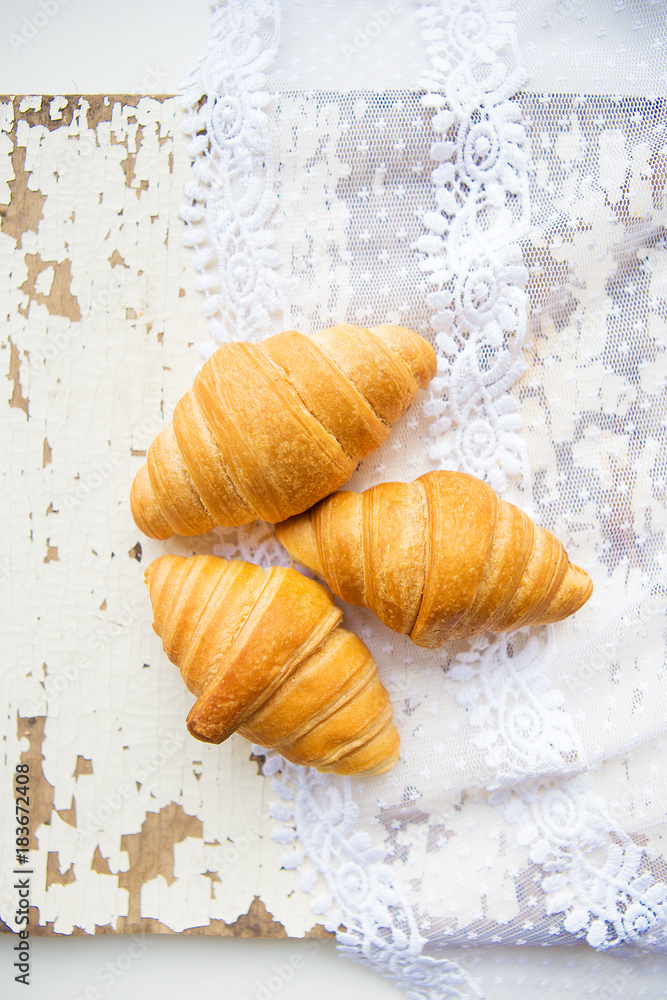 Beautiful and delicious croissants on the background of old laces and white table. Beautiful and delicious croissants on the background of old laces and white table.