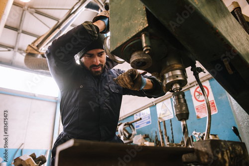 Worker at milling machine in workshop.