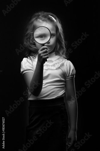 A little girl looks through a magnifying glass