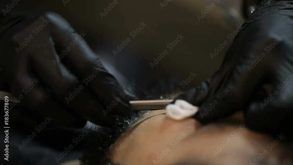 Master makes a haircut beard client with straight razor Master makes a haircut beard client with straight razor