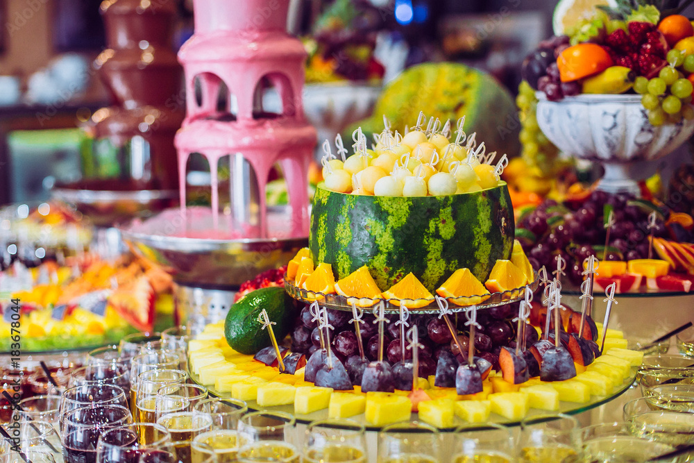 Delicious sweets and fruits on candy buffet. Lot of colorful desserts on table. Chocolate fountain. Party catering.