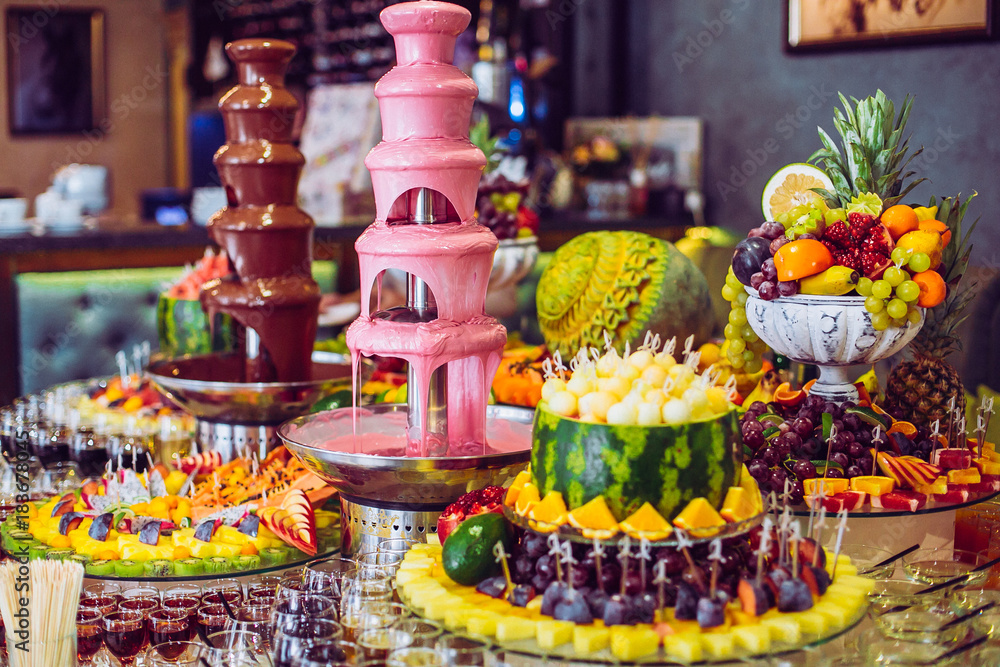 Delicious sweets and fruits on candy buffet. Lot of colorful desserts on table. Chocolate fountain. Party catering.
