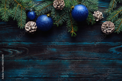 New Year and Christmas decorations Pine tree branches, cones, blue Christmas toys on a wooden background.