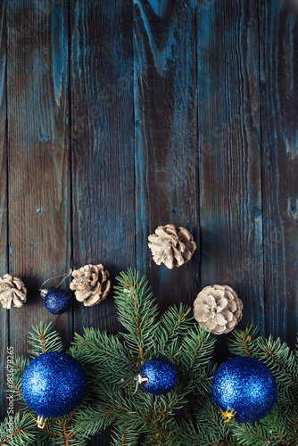 New Year and Christmas decorations Pine tree branches, cones, blue Christmas toys on a wooden background.