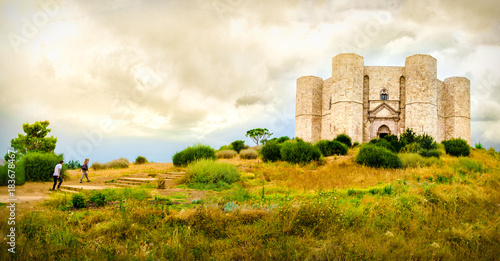 couple climb steps in a natural yellow landscape to reach  Castel del Monte in Apulia - Andria Trani province - Italy