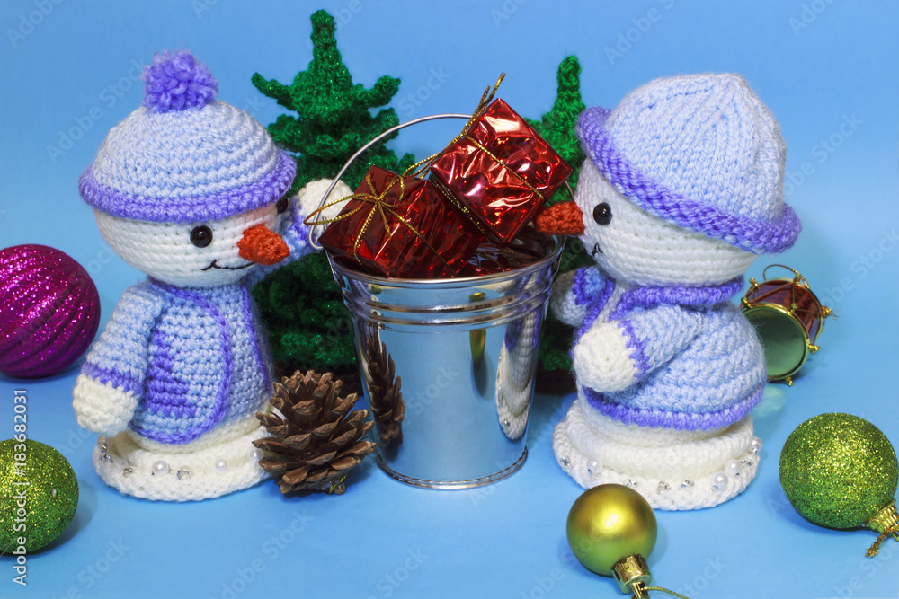 between two toy snowmen a bucket with gifts among the Christmas toys