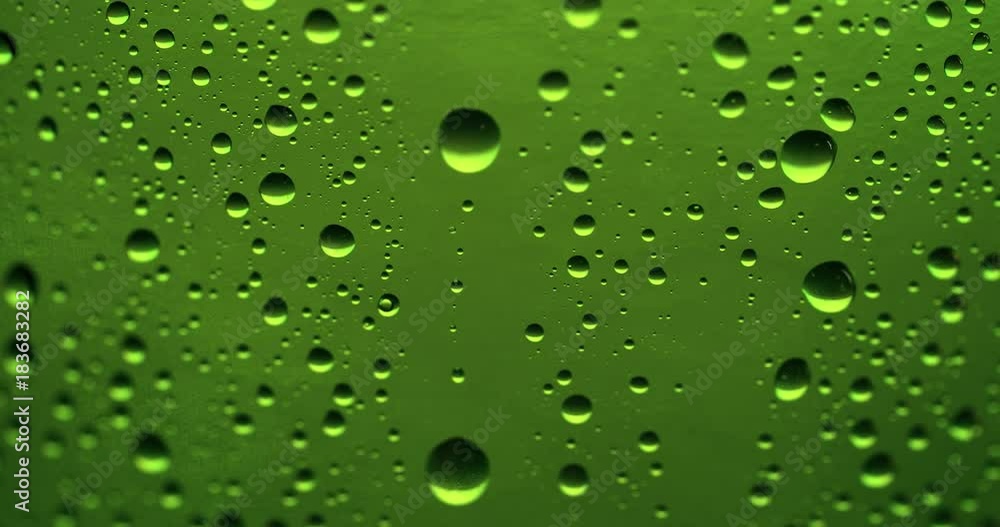 Drop of condensate drips on beer bottle glass 4k extreme close-up video. Water drops falling down on green background Drop of condensate drips on beer bottle glass 4k extreme close-up video. Water drops falling down on green background