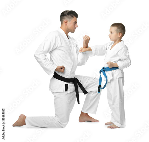 Little child with instructor practicing karate on white background