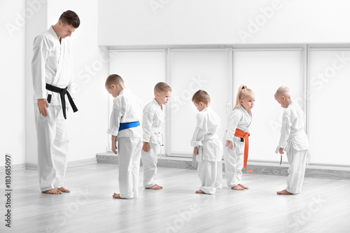 Little children and instructor performing ritual bow prior to practicing karate in dojo