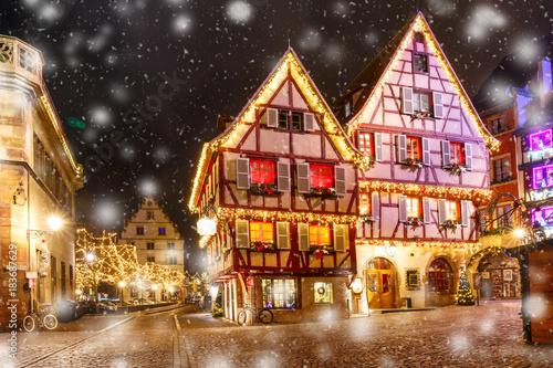 Traditional Alsatian half-timbered houses in old town of Colmar, decorated and illuminated at snowy christmas night, Alsace, France
