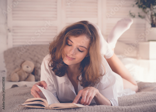  beautiful blond woman reading book in the bed. Relaxing concept