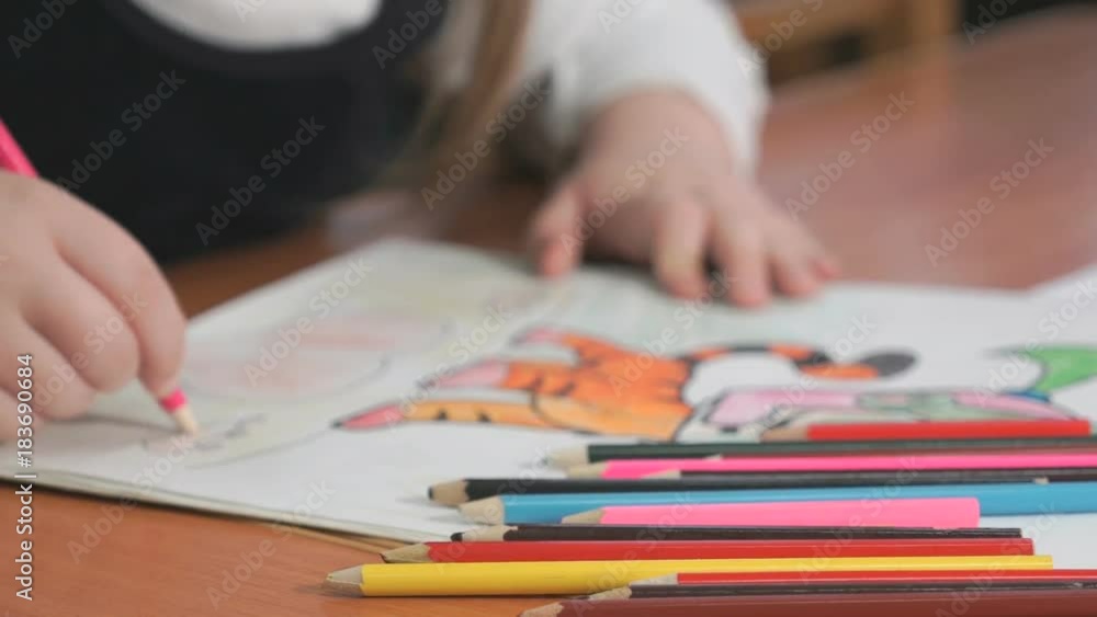 Close-up of unknown child draws the pictures using color pencils in the album in the kindergarten Close-up of unknown child draws the pictures using color pencils in the album in the kindergarten