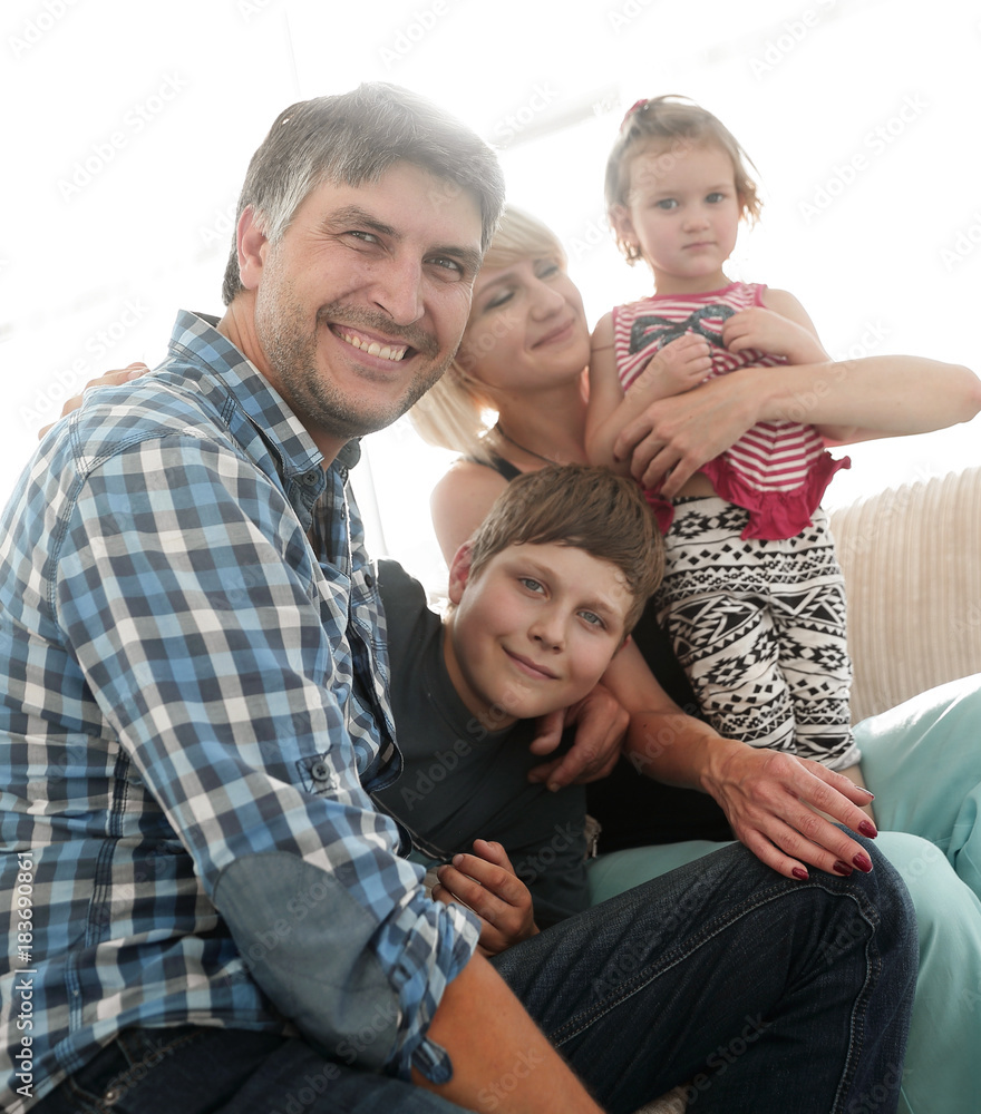 family with two children sitting together and looking at camera family with two children sitting together and looking at camera