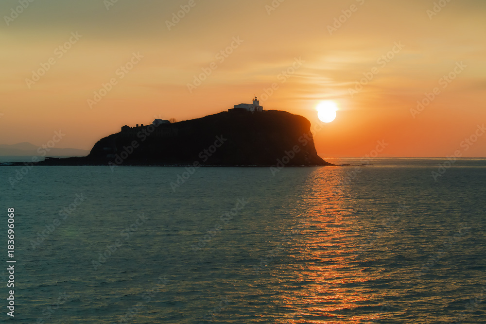 lighthouse on the island Skryplev in the light of the sunrise from the Harbor Parking of the city of Vladivostok