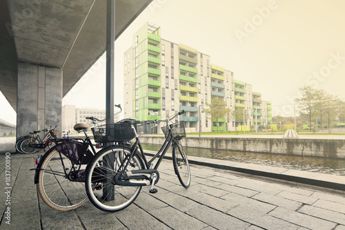 Пара велосипедов на берегу канала под бетонной опорой в Копенгагене. Дания